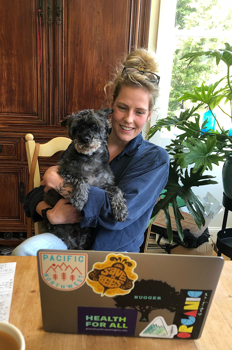 Tess Harpur in front of a laptop with her dog in her arms