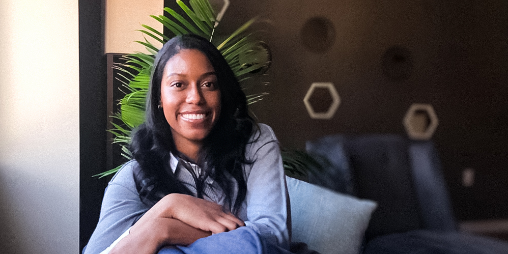 Shanise Owens smiling against a modern backdrop with plants