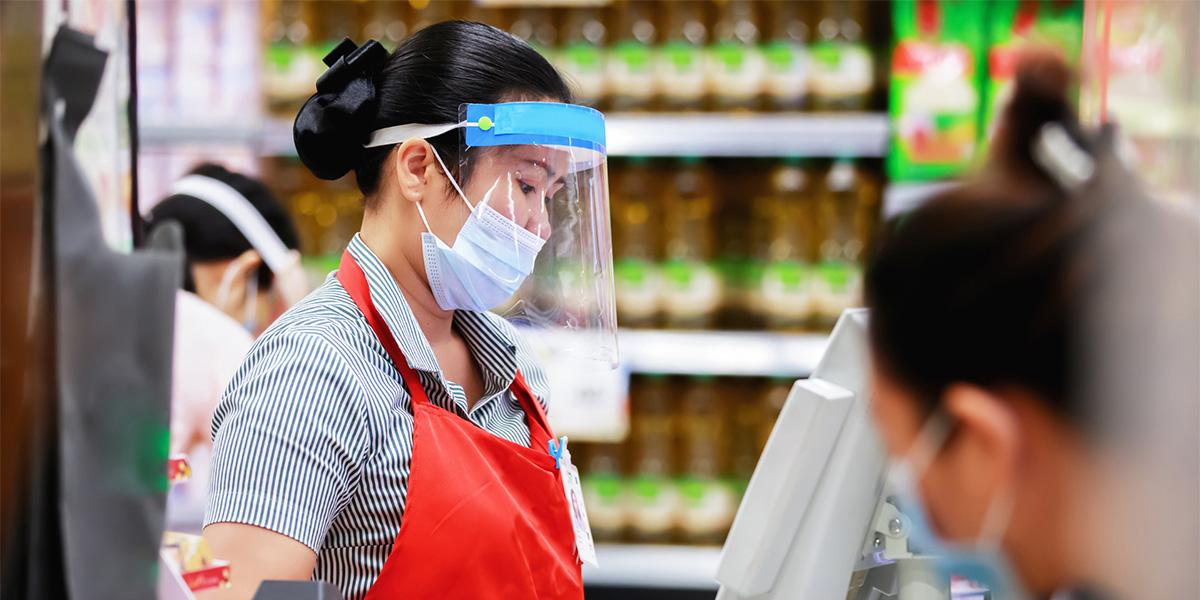 Essential grocery store worker wearing a face shield and mask