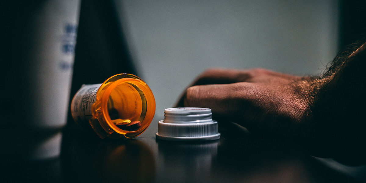 Opened pill bottle in a dramatic, high-contrast scene