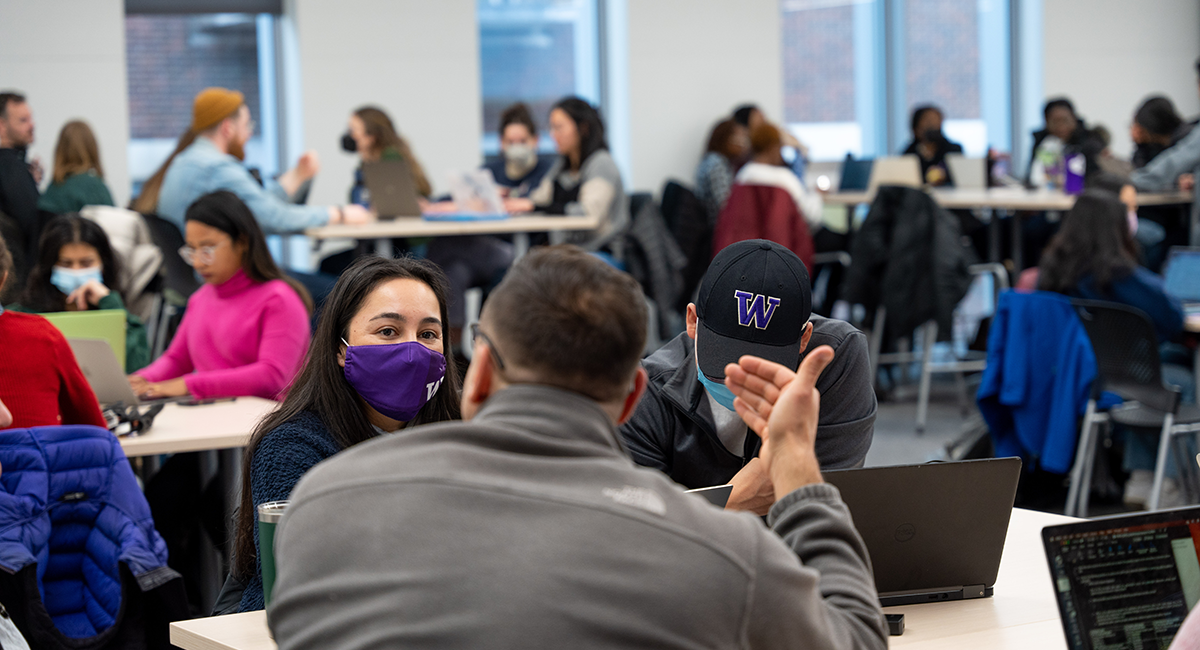 UW Students sitting around tables with laptops