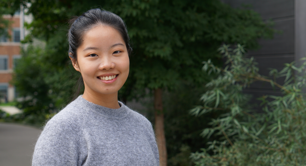 Yifan Lin stands in front of green shrubbery outside University of Washington building