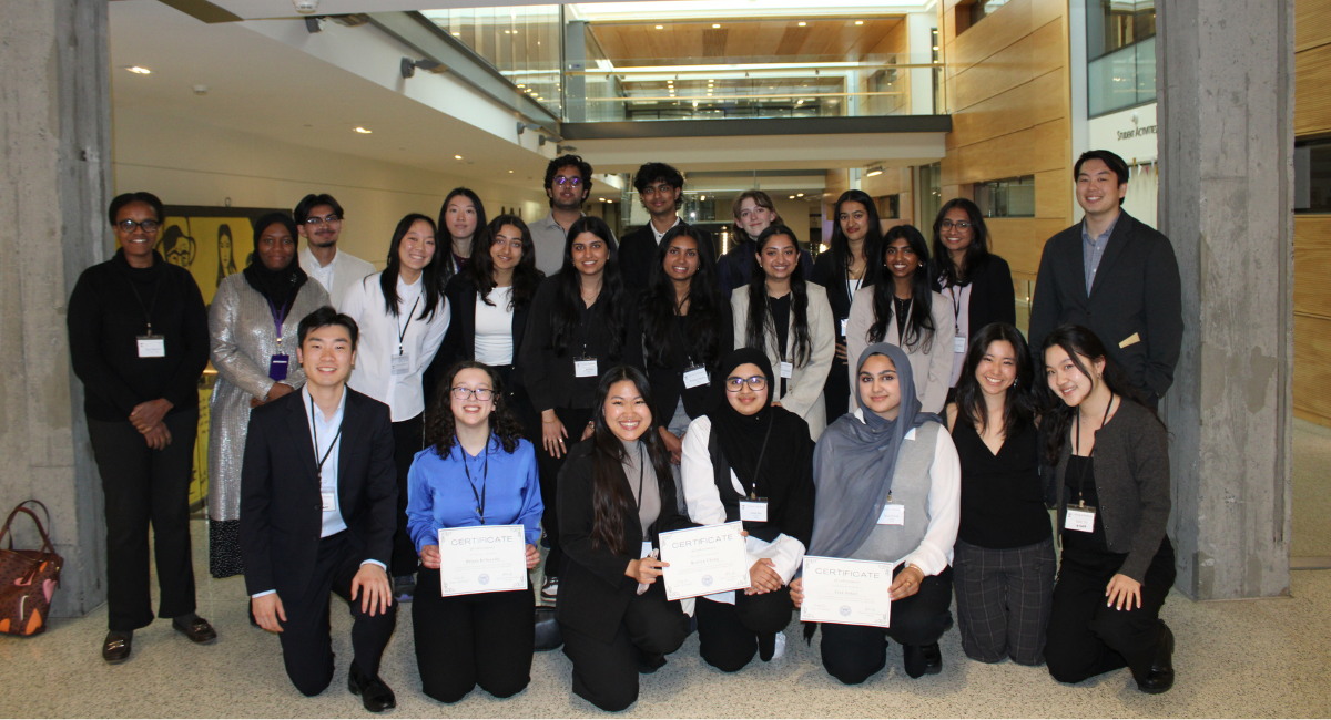 Dozens of students gather together and smile