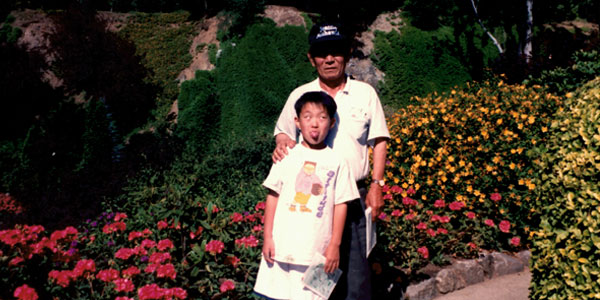 A young Phillip Hwang standing with his grandfather
