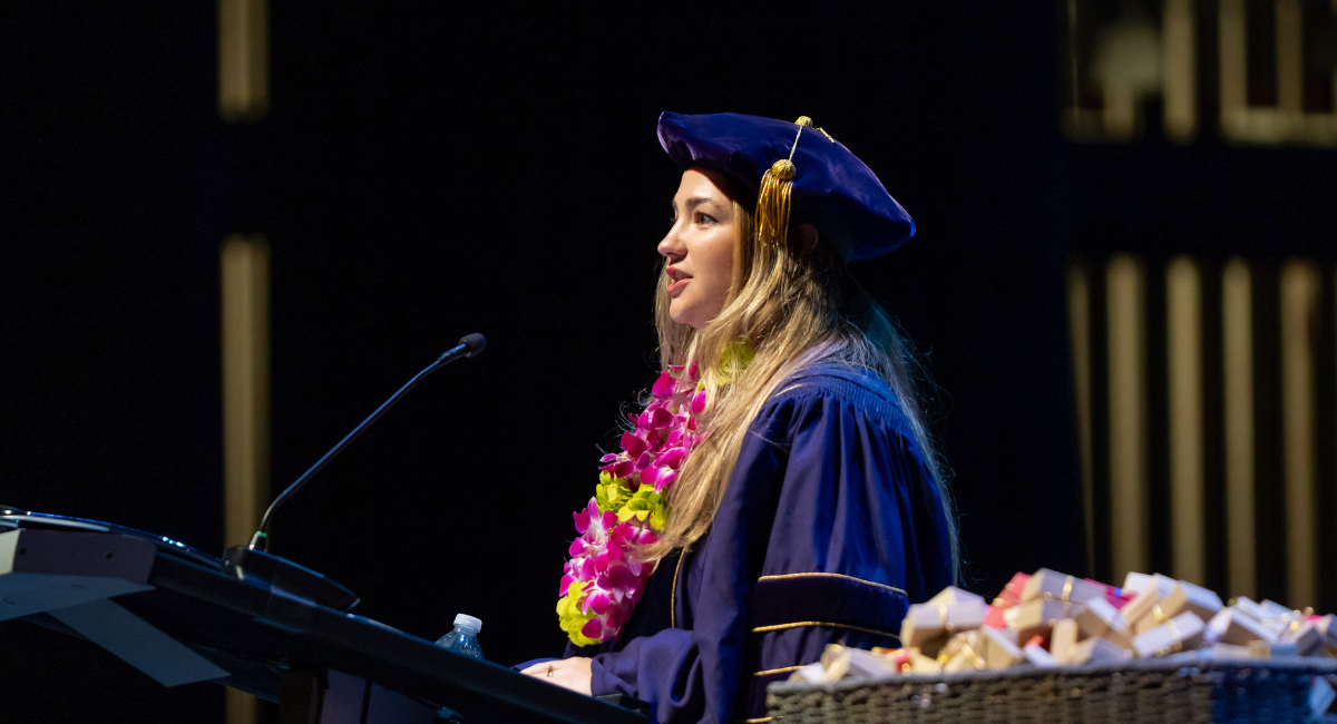 Taylor Rapson stands in front of podium in doctoral graduation attire