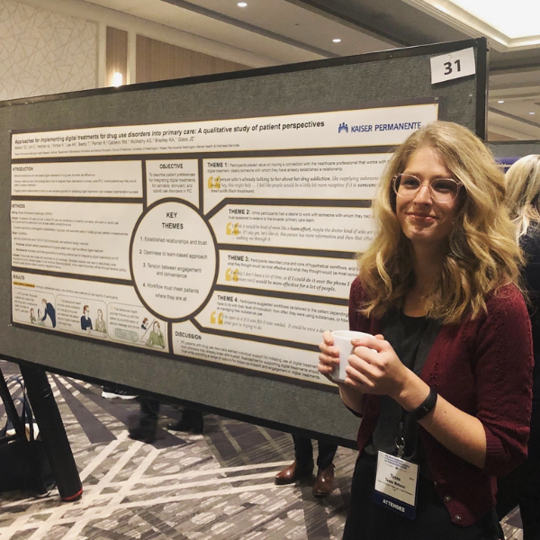 Tessa stands in front of poster at conference