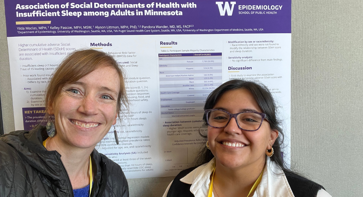 Yilda stands in front of poster at conference