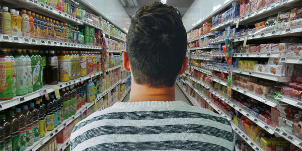 A man looks down the aisle of a grocery store.