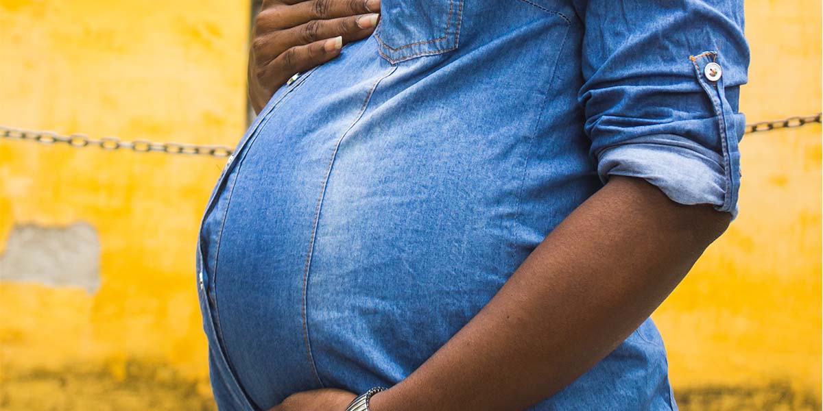 A pregnant woman cradles her baby bump