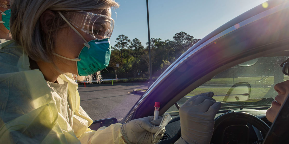 A tech performs a nasal swab on an active duty Airman during a COVID-19 screening.