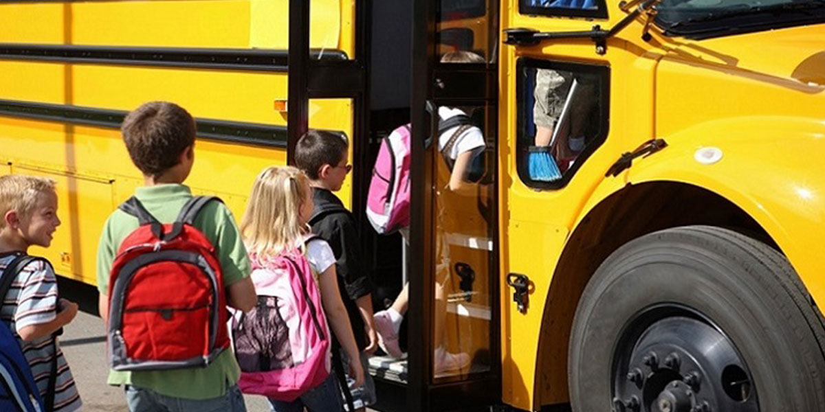 Kids line up to board a school bus.