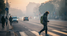 Person wearing mask crosses street under a hazy smokey orange sky