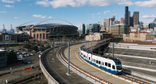 2 Line light rail train with Seattle buildings and stadium in background